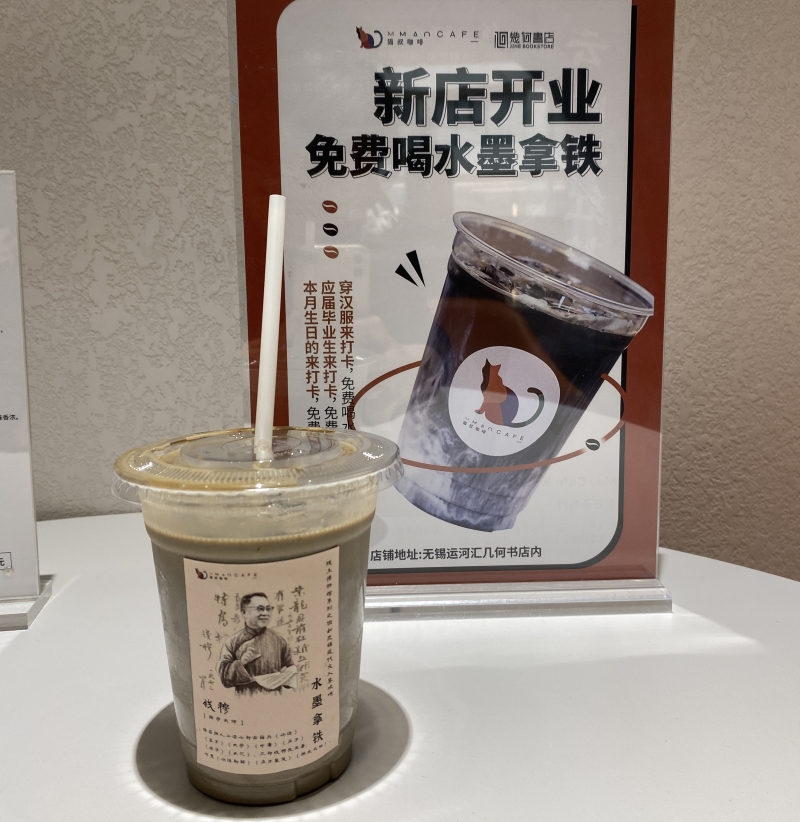 华侨城运河汇几何书店的水墨拿铁，杯子上贴着无锡人、国学大师钱穆演讲的画面和推荐书目